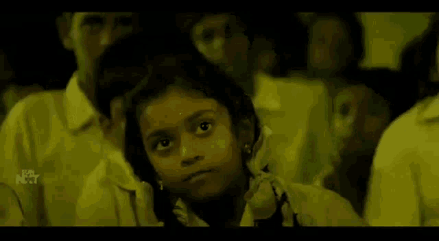 a group of children are standing in a dark room and a girl is yawning .