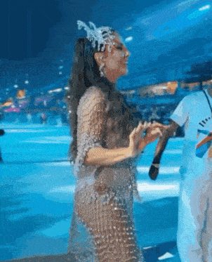 a woman in a very revealing dress is dancing in front of a crowd