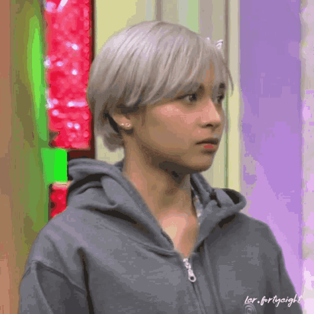 a man with white hair is wearing a grey hoodie with the words for forty-sight written on it