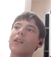a young boy wearing ear buds is looking up at something .