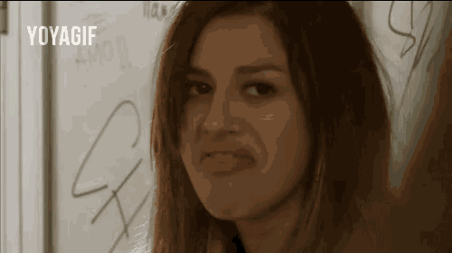 a woman is making a funny face in front of a wall with graffiti .