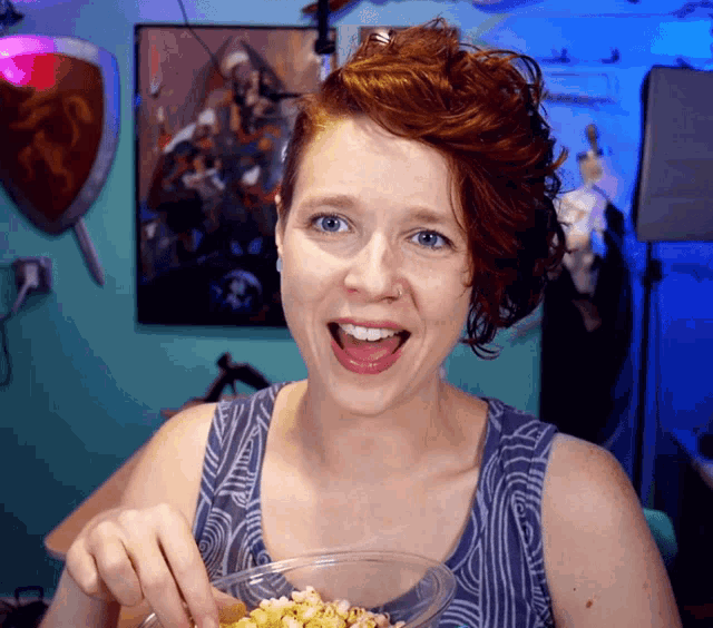 a woman in a blue tank top is eating popcorn