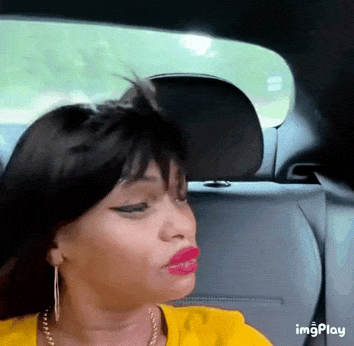 a woman in a yellow shirt is sitting in the back seat of a car