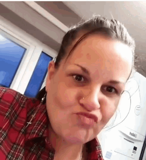 a woman in a plaid shirt is making a face in front of a yale appliance