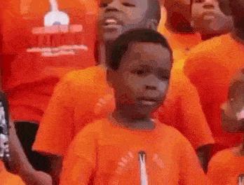 a group of children are singing in an orange choir .