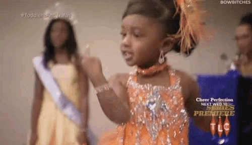 a little girl wearing an orange dress is giving the middle finger