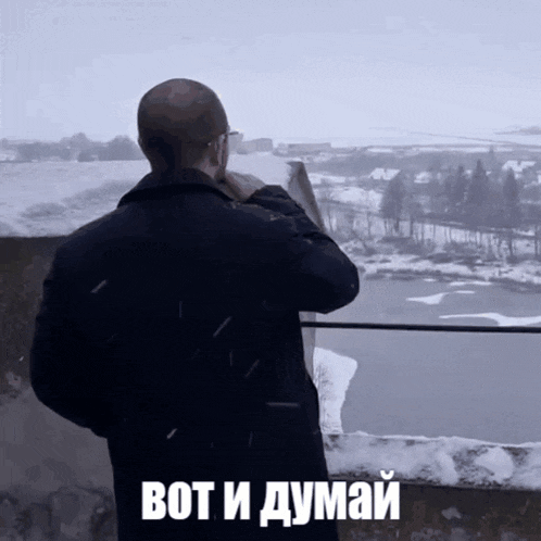a man standing on a balcony looking out over a snowy landscape with the words bot i думаy written on the bottom