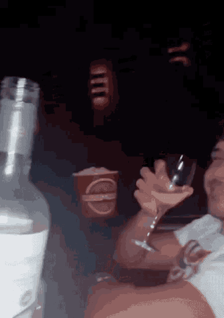 a man is holding a martini glass in front of a bottle of vodka