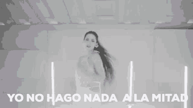 a woman in a white dress is standing in a room with the words yo no hago nada a la mitad written on the bottom