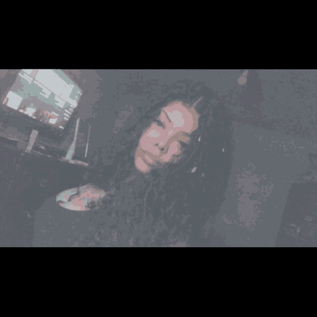 a woman with curly hair is taking a selfie in front of a tv