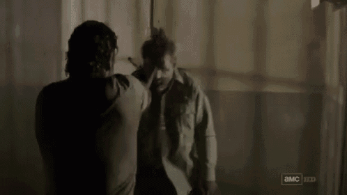 a man in a green shirt is standing next to another man in a room with a sign that says a & mc