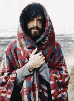 a man with a beard is wrapped in a colorful blanket with a hood