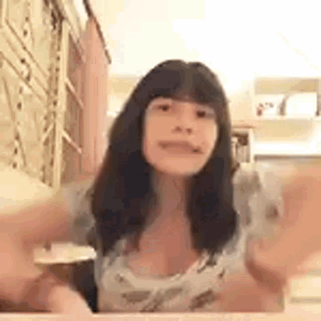 a woman is sitting at a table with her arms outstretched in front of a mirror .