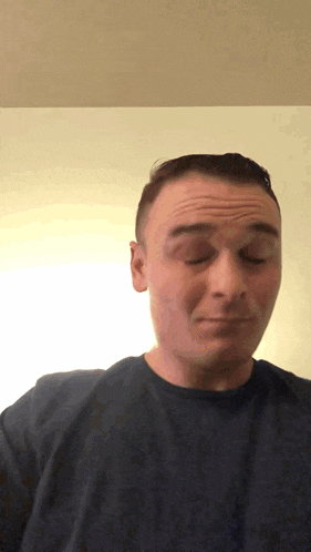 a man in a blue shirt is making a face with his eyes closed