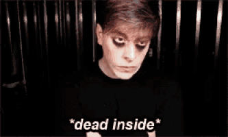 a man with black eye makeup is sitting in a dark room .