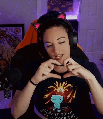 a woman wearing headphones and a shirt that says today is going to be a good day makes a heart shape with her hands