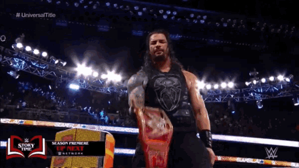 roman reigns is holding a shield in front of a crowd at a wrestling show