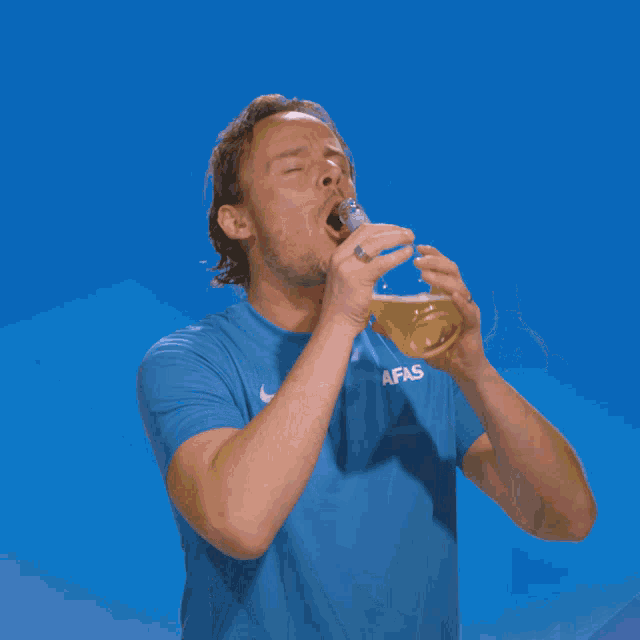 a man wearing a blue afas shirt drinks from a clear bottle