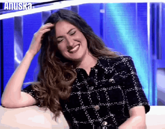 a woman in a plaid shirt is smiling and laughing with the word anuska behind her