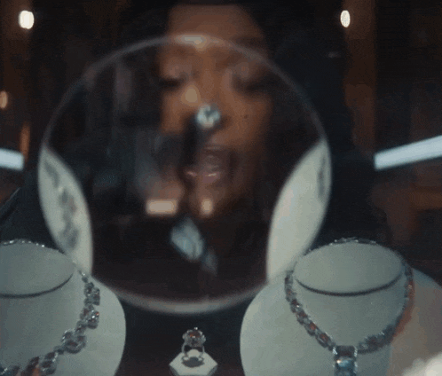 a woman is looking at necklaces and a ring in a store window