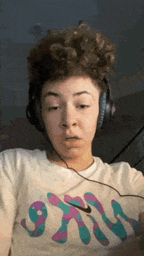 a young man wearing headphones and a nike shirt is making a face .