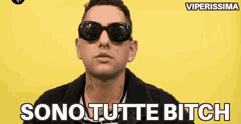 a man wearing sunglasses is standing in front of a yellow background and says sono tutte bitch .
