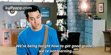a man in a blue shirt is sitting in a living room and talking to someone .