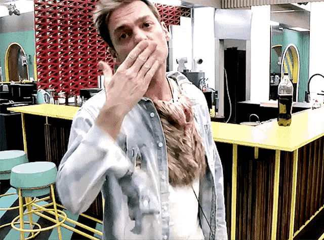 a man covering his mouth with his hand in front of a counter