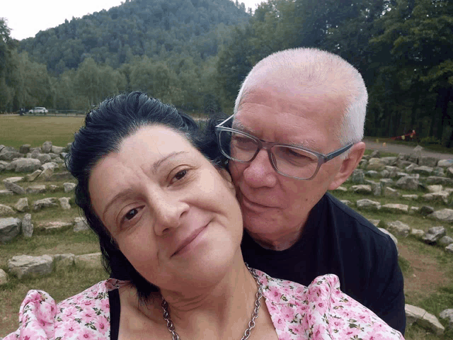 a man and a woman are posing for a picture and the woman is wearing glasses
