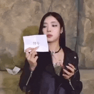 a woman in a black leather jacket is holding a piece of paper in her hand .