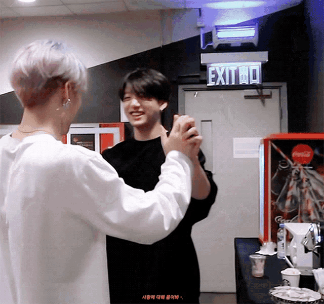 two men are dancing in front of a sign that says exit