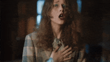 a woman in a plaid jacket is holding her chest with her hands