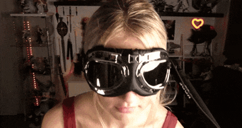 a woman wearing a pair of goggles with a heart shaped light in the background