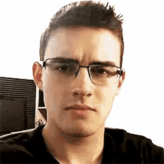 a young man wearing glasses and a black shirt is making a face .
