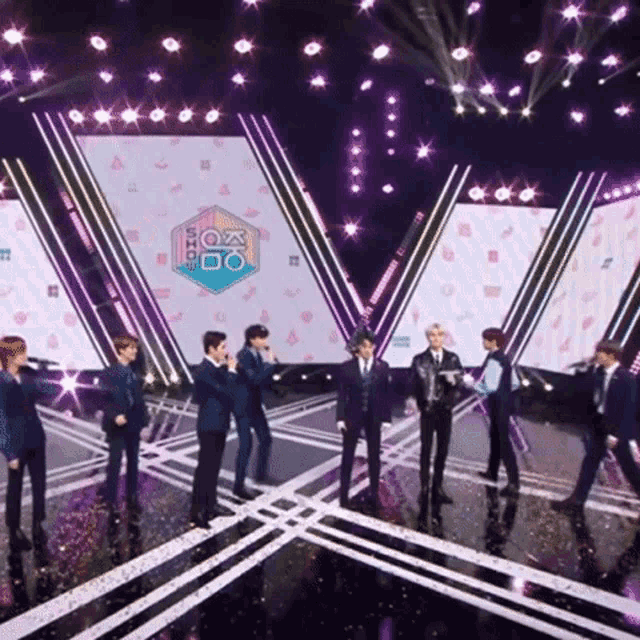 a group of men stand on a stage in front of a sign that says k-pop