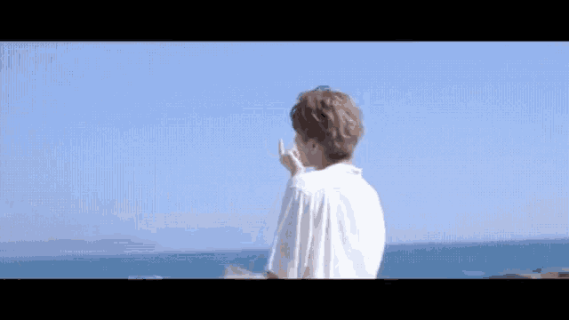 a man in a white shirt is standing in front of a body of water