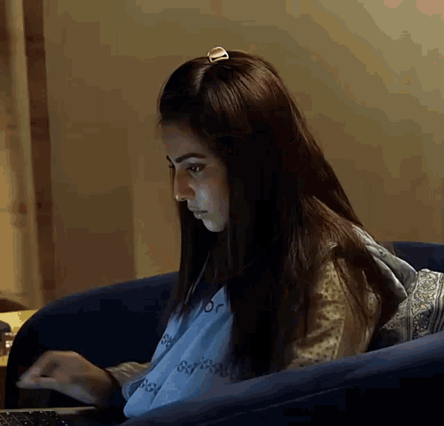 a woman is sitting in a chair and typing on a laptop .