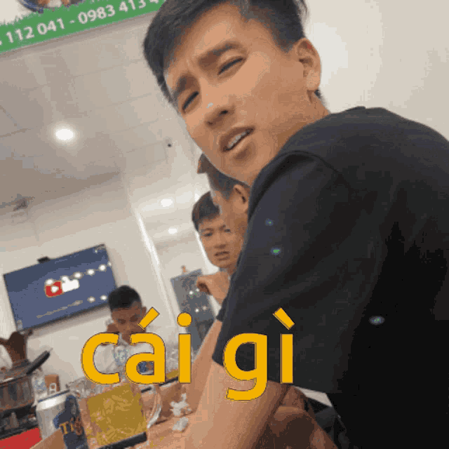 a man is sitting at a table with the word caigi on his arm