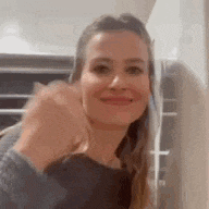 a woman is smiling and giving a fist bump while standing in a kitchen .