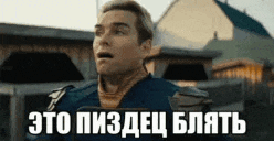 a man with a surprised look on his face is standing in front of a building with a sign in russian .
