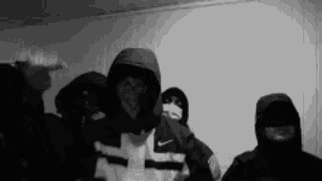 a black and white photo of a group of people wearing hoods and masks .