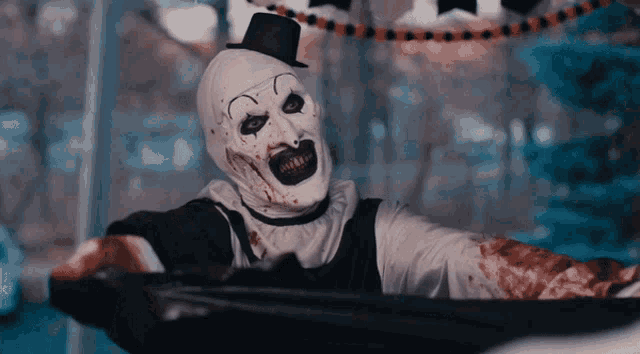 a clown with blood on his face and a top hat is holding a knife