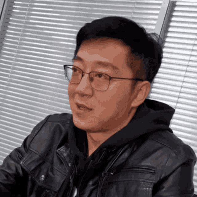 a man wearing glasses and a leather jacket