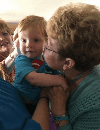 a woman holds a baby in her arms and kisses it on the cheek