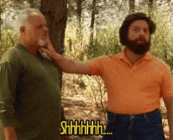 a man with a beard is touching another man 's neck while another man says " shhhh "
