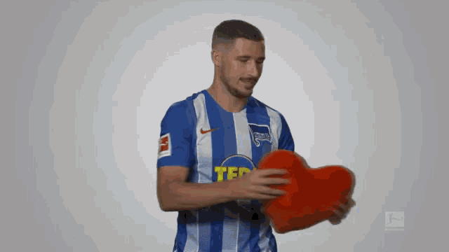 a man in a blue and white striped shirt holds a heart
