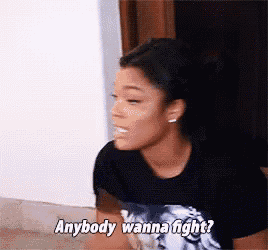 a woman in a black t-shirt is talking to someone and says `` anybody wanna fight ? ''
