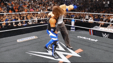 two wrestlers in a wrestling ring with a snickers advertisement