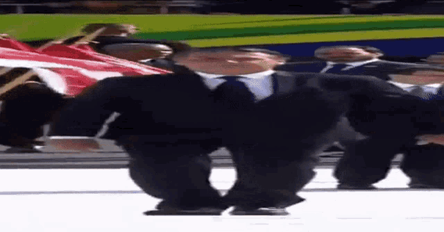 a man in a suit and tie is dancing in front of a group of people