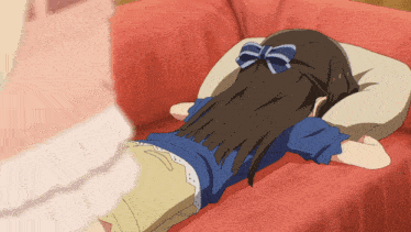 a girl with a blue bow in her hair lays on a red couch